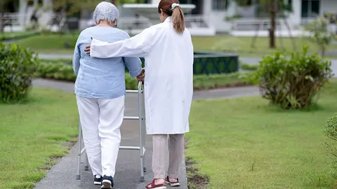 Mujer pasea con una profesional de una residencia de mayores (Foto: envato)